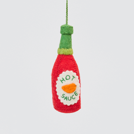 Craftspring’s handmade felt Hot Sauce ornament twirling to show its embroidered and applique details—playful holiday decor for spice lovers, sustainably crafted by artisans using wool.