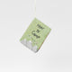 Hand-sewn felt ornament in the shape of a miniature book titled How to Camp, featuring embroidered pages with images of a tent, campfire, and fishing pole. Made from natural merino-blend wool, this whimsical ornament includes a hanging string and measures approximately 2.5 inches tall and 3 inches wide.