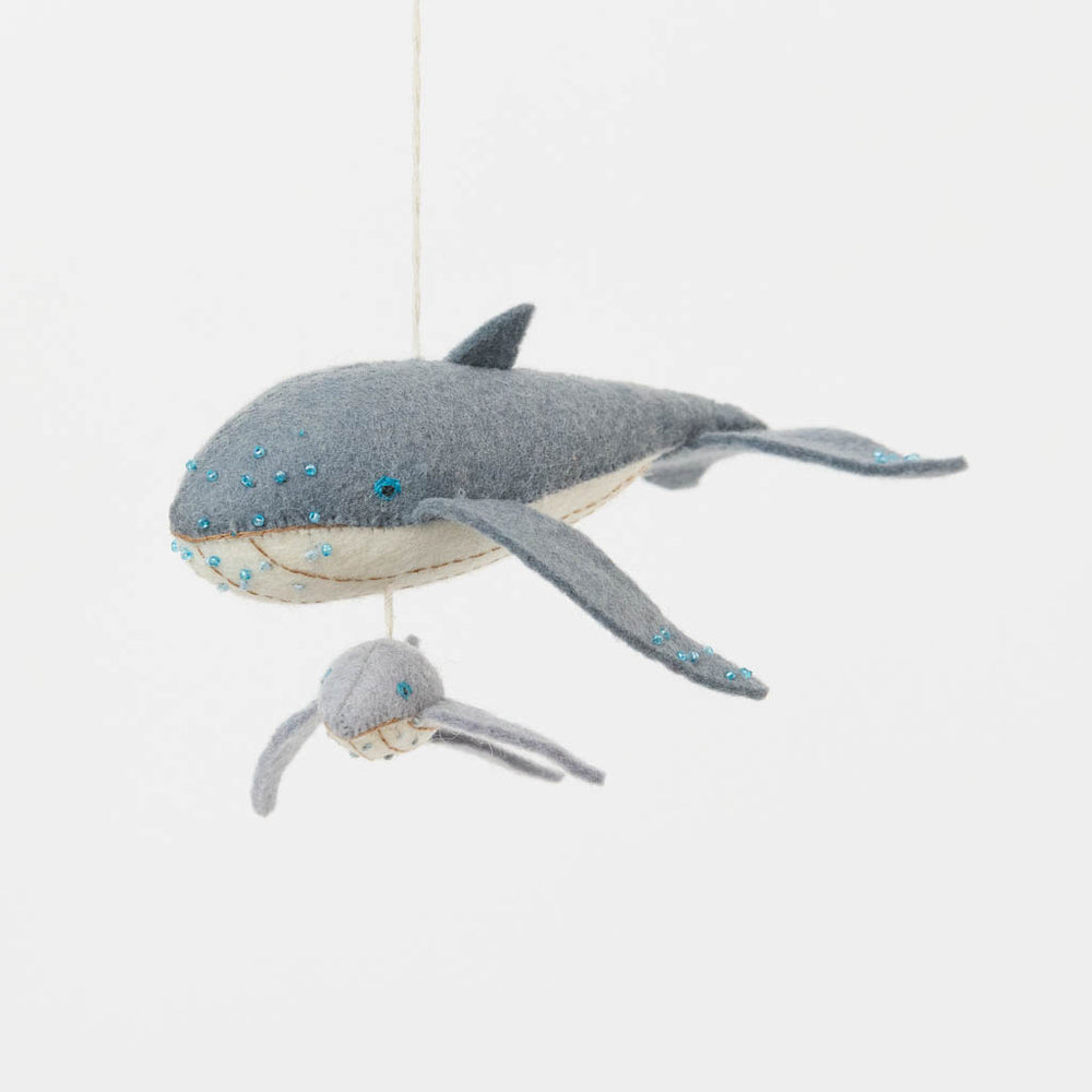 Graceful, gentle, and full of wonder, our Humpback Whale with Baby Ornament captures one of nature’s most touching sights—a mother whale guiding her calf through the open sea. Handcrafted from soft felted wool and accented with shimmering blue beadwork, this beautiful ornament celebrates the deep connection between parent and child while honoring the majestic marine life that frequents Maine’s coastal waters.