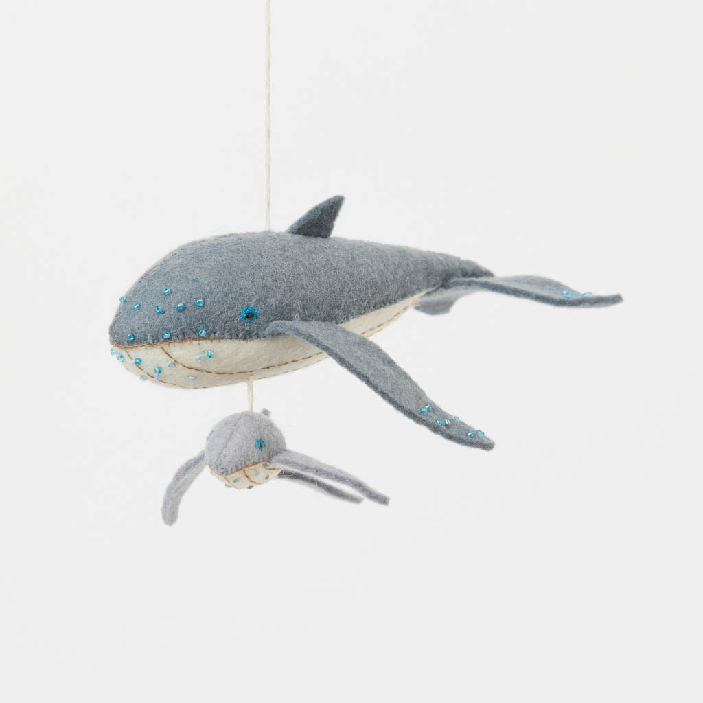 Graceful, gentle, and full of wonder, our Humpback Whale with Baby Ornament captures one of nature’s most touching sights—a mother whale guiding her calf through the open sea. Handcrafted from soft felted wool and accented with shimmering blue beadwork, this beautiful ornament celebrates the deep connection between parent and child while honoring the majestic marine life that frequents Maine’s coastal waters.