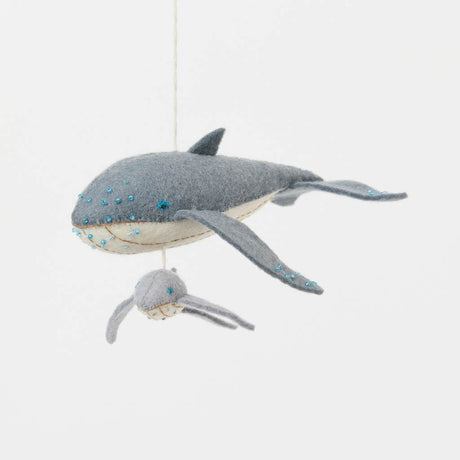 Graceful, gentle, and full of wonder, our Humpback Whale with Baby Ornament captures one of nature’s most touching sights—a mother whale guiding her calf through the open sea. Handcrafted from soft felted wool and accented with shimmering blue beadwork, this beautiful ornament celebrates the deep connection between parent and child while honoring the majestic marine life that frequents Maine’s coastal waters.