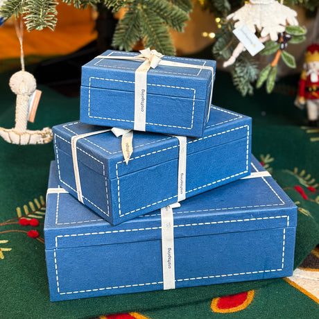 Craftspring’s blue gift boxes wrapped with twill ribbon, displayed under a Christmas tree—beautiful artisan-crafted packaging ready for meaningful, heirloom holiday gifting.