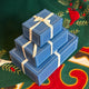 Craftspring’s set of three blue gift boxes wrapped with twill ribbon, displayed on a Christmas tree skirt—beautiful, high-quality packaging for festive holiday gifting, crafted by artisans with care.