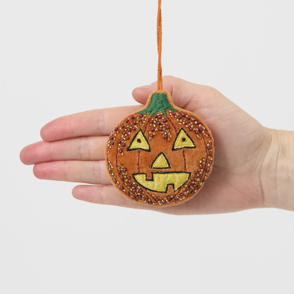 A vintage-inspired handmade beaded Jack O’Lantern Ornament featuring a smiling embroidered pumpkin face on one side and festive “Trick or Treat” detailing on the reverse.