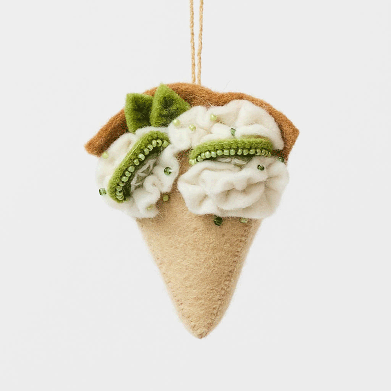 Capture the sweet taste of the Florida Keys with our handcrafted Key Lime Pie Slice Felt Ornament, a delightful dessert-inspired decoration featuring fluffy whipped cream, vibrant lime accents, and realistic pie slice details. Handmade from sustainable wool felt by women artisans, this whimsical ornament celebrates one of America's most beloved tropical desserts and adds a playful touch to holiday décor.