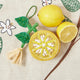 Hand-beaded lemon ornament with tasseled blossom and detailed leaves, backed with cotton-linen blend fabric.