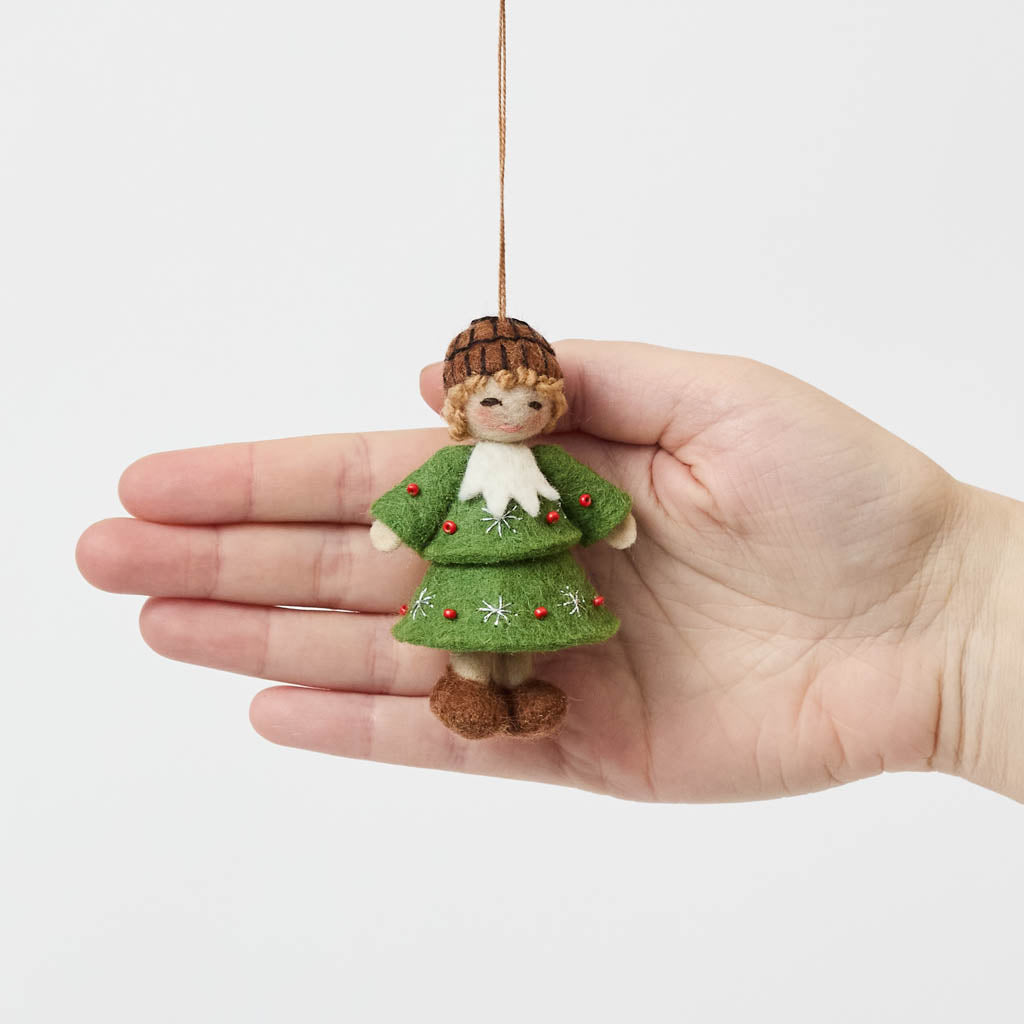 Inspired by the gentle wonder of Waldorf traditions, our Little Acorn Kid Ornament captures the whimsical spirit of a woodland fairy tale. Wearing an adorable felted acorn cap and a charming oak-leaf skirt.
