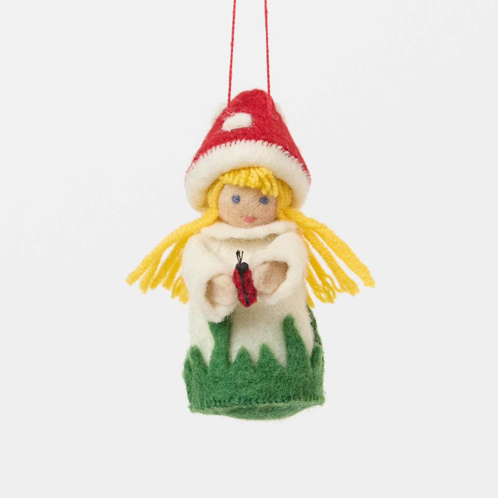 A magical little child of the forest, bringing good fortune, woodland wonder, and a sprinkle of fairy-tale enchantment into your home all year round! This sweet little red Amanita mushroom girl ornaments features a bright red felted mushroom cap, dotted with delicate white spots, and a skirt hemmed with felted green grasses. 
