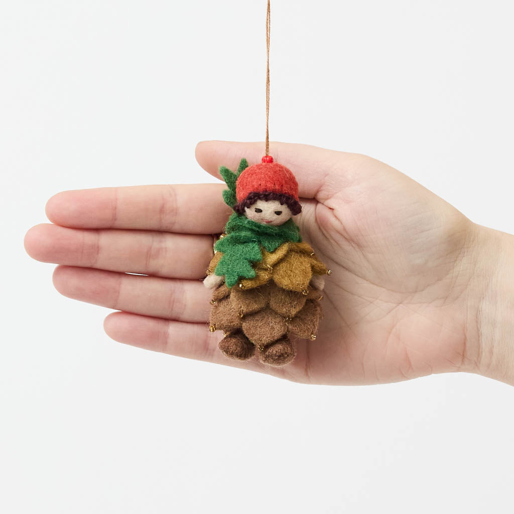 Waldorf-inspired, our Little Pinecone Kid Ornament captures the whimsical spirit of a woodland fairy tale. With its cute woolen bonnet, it's pine-green scarf and lovely layered pinecone petals and sweet as can be felted booties - this pinecone child is ready to capture woodland hearts.