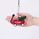Craftspring’s Little Red Wagon with Tree Ornament displayed in front of a hand to show its size — felt little red wagon carrying a Christmas tree and garland, with embroidered and beaded details, a charming heirloom-quality piece for Christmas gifting — ethically crafted by artisans using sustainable wool.