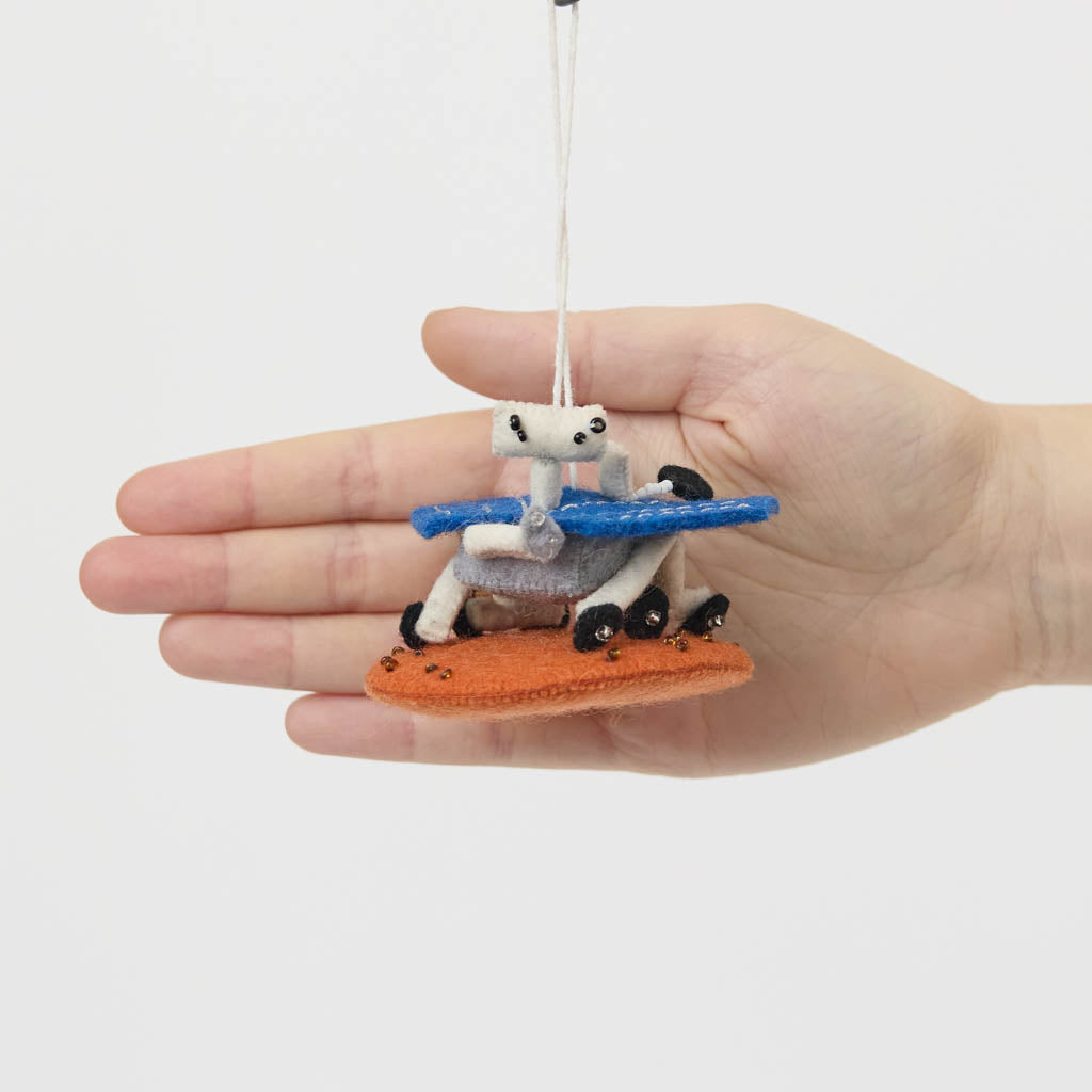 Explore the Red Planet with our handcrafted Mars Opportunity Rover Ornament, inspired by NASA’s legendary Mars Exploration Rover, affectionately known as "Oppy." Designed in soft wool felt with intricate handcrafted details, this ornament captures the iconic rover as it traverses the dusty Martian landscape in search of scientific discoveries.