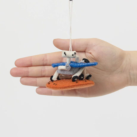 Explore the Red Planet with our handcrafted Mars Opportunity Rover Ornament, inspired by NASA’s legendary Mars Exploration Rover, affectionately known as "Oppy." Designed in soft wool felt with intricate handcrafted details, this ornament captures the iconic rover as it traverses the dusty Martian landscape in search of scientific discoveries.
