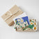 Merci Gift Box Set featuring a felt blueberry ornament, white daisy flower bouquet in vase, and daisy greeting card. Handmade from wool felt with French-inspired floral charm. Fair trade and ready to gift.