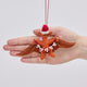 Handmade felt Merry Pterodactyl ornament from Craftspring held in front of a hand to show size—featuring embroidered details, a red Santa hat, and a festive “MERRY” garland, perfect for dino-loving kids and playful holiday gifting, ethically crafted using sustainable wool.