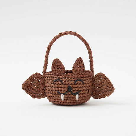 A hand-crocheted raffia Mini Bat Basket featuring playful wings, pointed ears, tiny fangs, and a sweet embroidered face for Halloween treats, treasures, and imaginative play.
