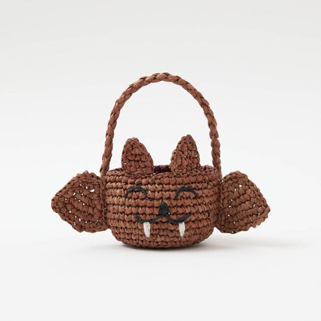 A hand-crocheted raffia Mini Bat Basket featuring playful wings, pointed ears, tiny fangs, and a sweet embroidered face for Halloween treats, treasures, and imaginative play.
