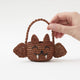 A hand-crocheted raffia Mini Bat Basket featuring playful wings, pointed ears, tiny fangs, and a sweet embroidered face for Halloween treats, treasures, and imaginative play.