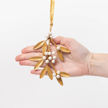 Add a little holiday romance to the tree with our Mistletoe Metal Ornament. Inspired by vintage botanical decorations, this delicate golden mistletoe is beautifully handcrafted with embossed iron leaves, hand-cast resin details, and a softly aged gilt finish.