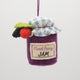 Hand-felted wool ornament of a berry jam jar with a red gingham-patterned lid, topped with beaded blackberry and raspberry accents. Crafted with embroidered details and soft textures, it includes a hanging string and measures approximately 2.75 inches high. A sweet, handmade tribute to homemade preserves and cozy kitchen moments.