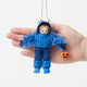 A handmade felt Monster Trick-or-Treater Ornament featuring a child dressed in a fuzzy blue monster costume and carrying a miniature jack-o’-lantern candy bucket.