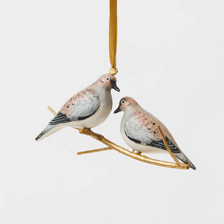 Two little doves, perched side by side. Our Mourning Doves Ornament captures one of nature’s sweetest pairings, with two beautifully hand-painted birds resting together on a delicate gold-toned metal branch.