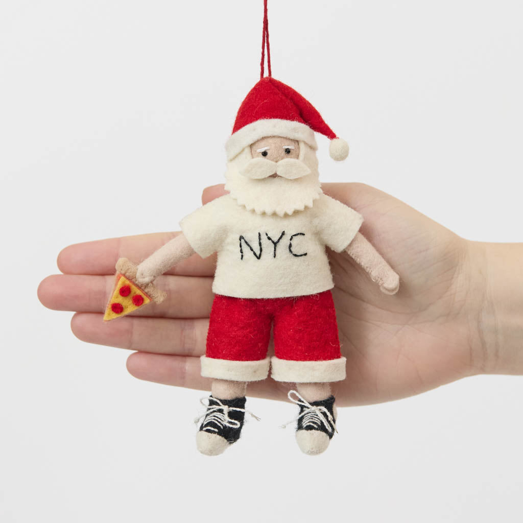 Celebrate Christmas in the Big Apple with our handmade NYC Santa Ornament, featuring Santa dressed like a true New Yorker with an NYC tee and a classic slice of New York pizza.

Who says Santa only runs on milk and cookies? After a busy night delivering gifts across the five boroughs, he's treating himself to a well-earned slice of New York pizza.