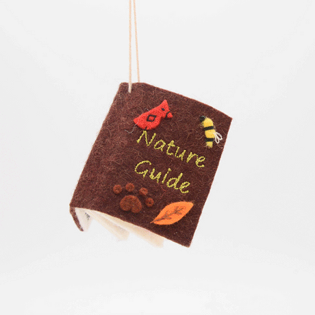 Handmade felt Nature Guide ornament from Craftspring spinning to show front, side, and back covers—featuring embroidered details inspired by plants and wildlife, ethically crafted by artisans using sustainable wool.