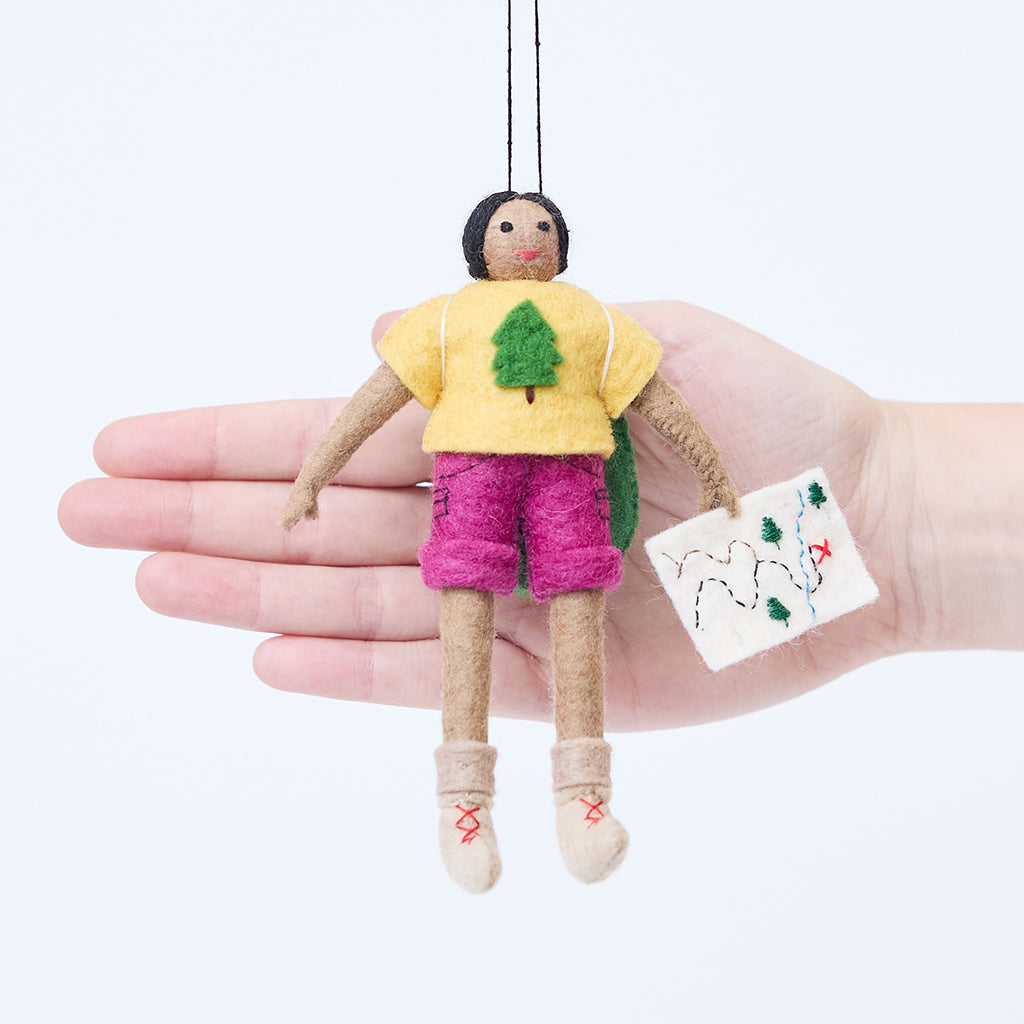 Craftspring’s On the Trail Backpacker Ornament – Brown displayed in front of a hand to show its size—handmade felt backpacker girl holding a map, heirloom-quality Christmas ornament, perfect for holiday gifting, ethically handcrafted by artisans using sustainable wool.