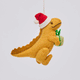 Handmade felt Orange T-Rex Dinoclaus ornament from Craftspring rotating to show front, side, and back views—featuring an orange dinosaur wearing a red Santa hat and holding a green present, perfect for dino-loving kids and playful holiday gifting, ethically crafted by artisans using sustainable wool.
