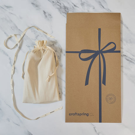 Craftspring packaging for Vintage-Style Angel Bundle of three angel ornaments, featuring a branded mailer and protective cloth bag displayed on a marble surface — ready to safely deliver handmade felt holiday decor with beaded and embroidered details, ethically crafted by artisans using sustainable wool.