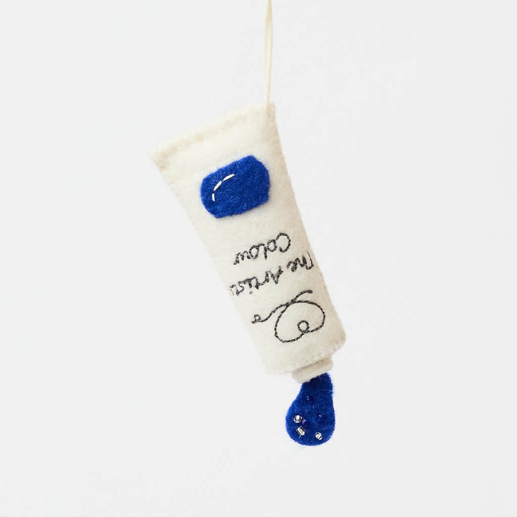 Add a splash of creativity to your holiday décor with our handcrafted Paint Tube Ornament. Designed for artists, makers, and color lovers, this charming felt ornament captures the playful essence of a classic paint tube—complete with a vibrant blue “paint” drop detail. On the back, intricate embroidery mimics a real paint label—complete with ‘Primary Blue #287’ markings and barcode-style details—adding an extra layer of realism and handcrafted charm.
