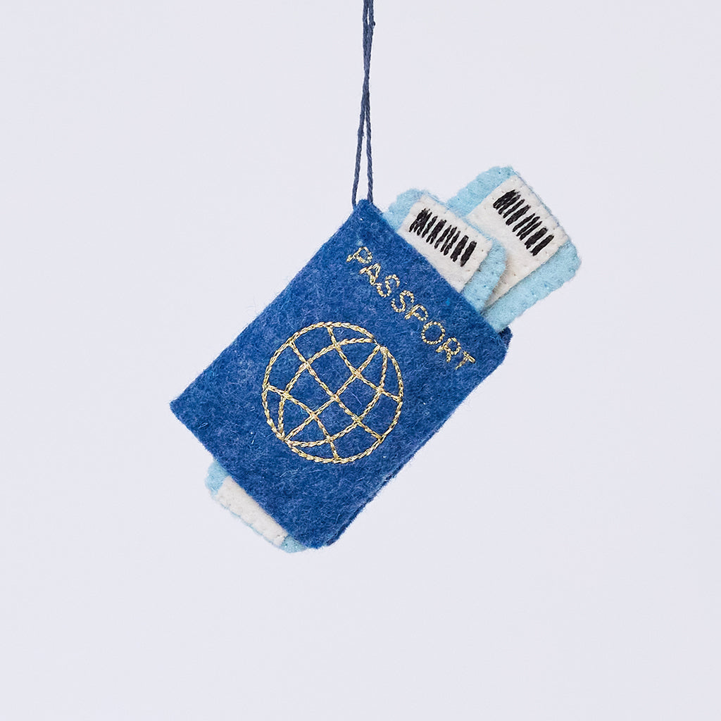 Handmade felt Passport ornament from Craftspring, featuring applique and embroidered details with two plane tickets tucked inside and passport stamps on the back—heirloom-quality Christmas decor, ethically crafted by artisans using sustainable wool.