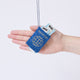 Craftspring’s Passport ornament held in front of a hand to show its size—handmade from sustainable wool with applique and embroidered details, two plane tickets tucked inside, and passport stamps on the back, ethically crafted by artisans using sustainable wool.