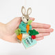 Handmade wool ornament of Peter Rabbit, featuring the beloved children's book character sitting with a carrot in one paw and an embroidered book on his lap. He wears his signature blue jacket, crafted with detailed stitching. Made from natural felted merino-blend wool, the ornament is ready to hang and sized approximately 4.5 inches tall. With a hand for scale