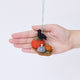 Craftspring’s Pumpkin Patch ornament held in front of a hand to show its size—handmade from sustainable wool with three pumpkins in different colors and a crow perched on top, with beaded and embroidered details, ethically crafted by artisans using sustainable wool.