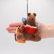 Handmade felt ornament featuring a cozy scene with a bear reading a book, surrounded by woodland friends. Crafted from eco-friendly wool, this ornament captures the magic of shared reading and childhood adventures. A heartwarming gift for book-loving families, young readers, and those who cherish the joy of storytelling. Ready to hang with a string attached, it adds a whimsical touch to holiday trees and reading spaces. Hand for size scale comparison.