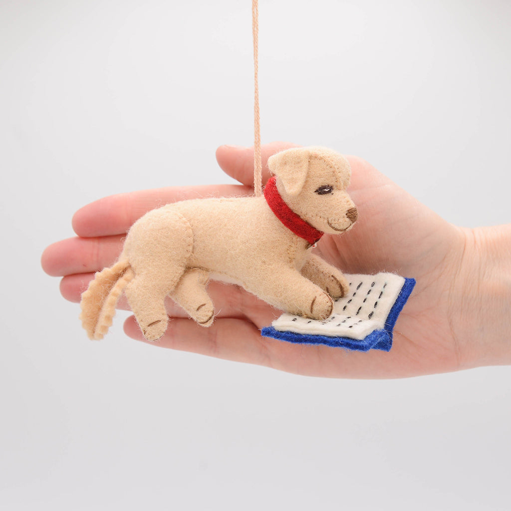 Whimsical reading dog ornament crafted from natural wool – perfect for celebrating the quiet joy of reading and story time rituals.