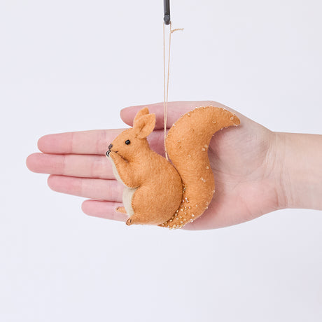 Craftspring’s Red Squirrel ornament held in front of a hand to show its size—handmade from sustainable wool with delicate beaded and embroidered details, ethically crafted by artisans using sustainable wool.