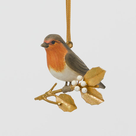 A vintage-inspired Robin Ornament, featuring a hand-painted red-breasted bird perched on a golden metal holly branch with white berries.