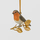 A vintage-inspired Robin Ornament, featuring a hand-painted red-breasted bird perched on a golden metal holly branch with white berries.