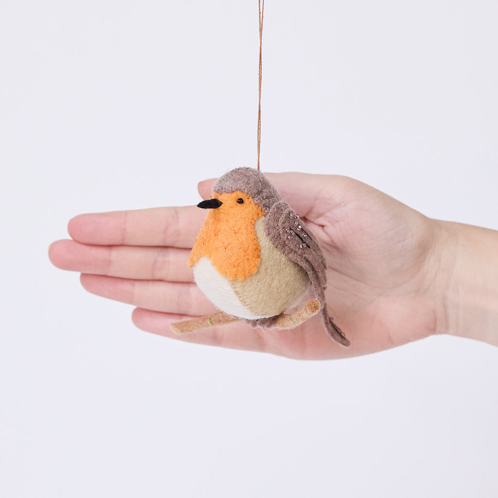 Craftspring’s European Robin ornament held in front of a hand to show its size—handmade from sustainable wool with delicate beaded and embroidered details, ethically crafted by artisans using sustainable wool.