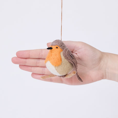 Craftspring’s European Robin ornament held in front of a hand to show its size—handmade from sustainable wool with delicate beaded and embroidered details, ethically crafted by artisans using sustainable wool.