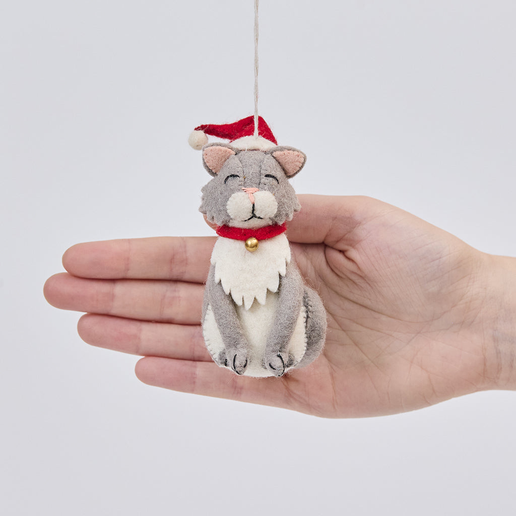 Handmade felt Santa Cat ornament from Craftspring held in front of a hand to show its size—featuring a gray cat wearing a red Santa hat with detailed stitching, bringing cozy Christmas warmth and perfect for cat lovers and thoughtful gifting, ethically crafted by artisans using sustainable wool.
