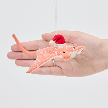 Craftspring’s Santa Coral Manta ornament held in front of a hand to show its size—handmade from sustainable wool with beaded and embroidered Christmas details, crafted by skilled artisans.