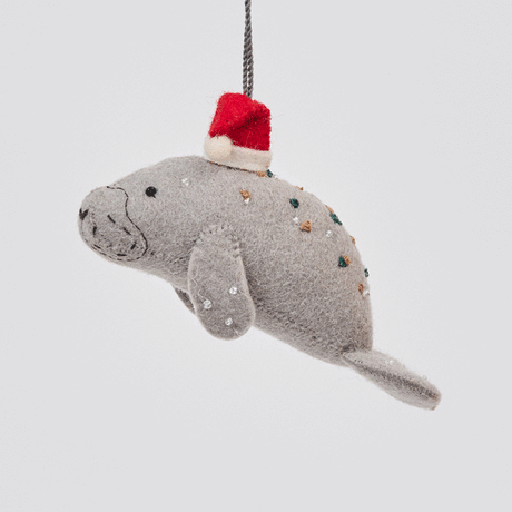 Handmade felt Santa Manatee ornament from Craftspring rotating to show front, side, and back views—highlighting the red Santa hat and detailed beadwork and embroidery, sustainably crafted by artisans.