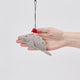 Handmade felt Santa Manatee ornament from Craftspring held in front of a hand to show its size—featuring a red Santa hat and intricate beaded and embroidered details, ethically crafted by artisans using sustainable wool.