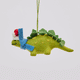 Handmade felt Santa Stegosaurus ornament from Craftspring shown from front, side, and back views—featuring a green dinosaur with embroidered spots, a red Santa hat, and a blue scarf, ethically crafted by artisans using sustainable wool for whimsical holiday decor.