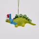 Handmade felt Santa Stegosaurus ornament from Craftspring, featuring a green dinosaur with embroidered spots, a red Santa hat, and a cozy blue scarf—whimsical holiday decor ethically crafted by artisans using sustainable wool.