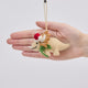 Handmade felt Santa Triceratops ornament from Craftspring held in front of a hand to show size—featuring embroidered and beaded details, a red Santa hat, and a green scarf, showcasing artisan craftsmanship and festive holiday charm, ethically crafted using sustainable wool.