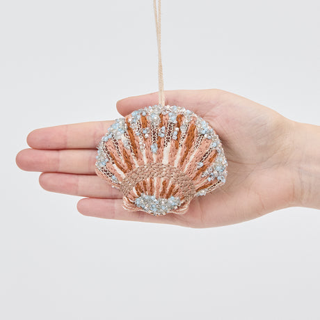 Craftspring’s Scallop Shell Ornament displayed in front of a hand to show its size — made of satin with intricate beaded and embroidered details, ethically crafted by artisans.